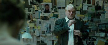 Movie still from “A Most Wanted Man” (2014), directed by Anton Corbijn – A man standing in front of a wall covered with papers; Medium shot, Over the shoulder angle