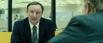 Movie still from “A Most Wanted Man” (2014), directed by Anton Corbijn – An older man in a suit and tie is sitting at a table; Close Up shot, Over the shoulder angle
