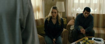 Movie still from “A Most Wanted Man” (2014), directed by Anton Corbijn – A woman sitting on top of a couch in a living room; Medium shot, Over the shoulder angle