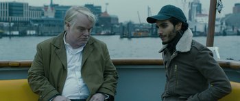 Movie still from “A Most Wanted Man” (2014), directed by Anton Corbijn – A man and a woman sitting next to each other on a boat; Close Up shot, Over the shoulder angle