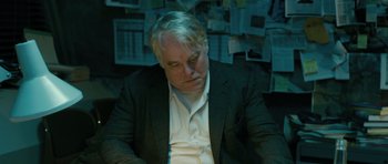 Movie still from “A Most Wanted Man” (2014), directed by Anton Corbijn – A man in a suit sitting in front of a wall; Close Up shot, Over the shoulder angle