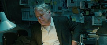 Movie still from “A Most Wanted Man” (2014), directed by Anton Corbijn – A man in a suit sitting in front of a wall; Medium shot, Over the shoulder angle