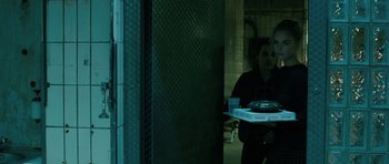 Movie still from “A Most Wanted Man” (2014), directed by Anton Corbijn – A person holding a box of pizza in a dark room; Medium shot, Over the shoulder angle