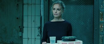 A woman standing in front of a box of pizza