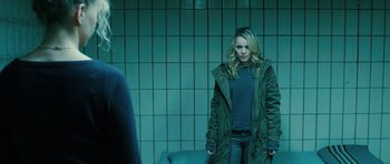 Movie still from “A Most Wanted Man” (2014), directed by Anton Corbijn – A woman standing in front of a wall with her hands in her pockets; Medium shot, Over the shoulder angle