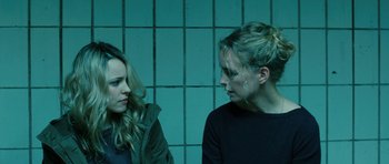 Movie still from “A Most Wanted Man” (2014), directed by Anton Corbijn – Two women standing next to each other in front of tiled walls; Close Up shot, Over the shoulder angle