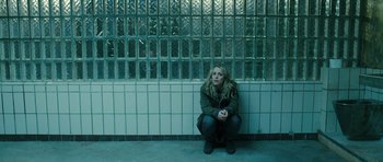 Movie still from “A Most Wanted Man” (2014), directed by Anton Corbijn – A woman sitting on the ground in front of a wall; Wide shot, High angle
