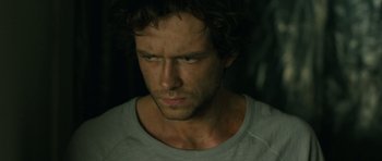 Movie still from “A Most Wanted Man” (2014), directed by Anton Corbijn – A person wearing a white t - shirt; Close Up shot, Over the shoulder angle