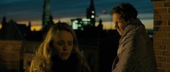 Movie still from “A Most Wanted Man” (2014), directed by Anton Corbijn – A man and a woman standing next to each other; Medium shot, Over the shoulder angle