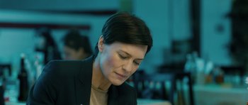 Movie still from “A Most Wanted Man” (2014), directed by Anton Corbijn – A person with short hair looking down; Close Up shot, Over the shoulder angle