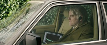 Movie still from “A Most Wanted Man” (2014), directed by Anton Corbijn – A man sitting in the drivers seat of a car with a laptop; Medium shot, Over the shoulder angle