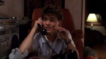 Movie still from “A Nightmare on Elm Street” (1984), directed by Wes Craven – A young man sitting at a table talking on a phone; Close Up shot, High angle