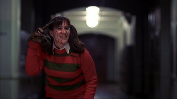 Movie still from “A Nightmare on Elm Street” (1984), directed by Wes Craven – A woman in a red and green sweater holding a knife and looking at the camera; Medium shot, Low angle