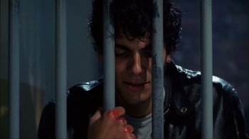 Movie still from “A Nightmare on Elm Street” (1984), directed by Wes Craven – A man in a leather jacket behind a metal fence; Close Up shot, Overhead angle