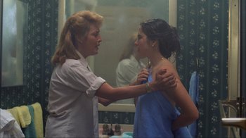 Movie still from “A Nightmare on Elm Street” (1984), directed by Wes Craven – A woman is helping another woman put on a necklace; Medium shot, Over the shoulder angle