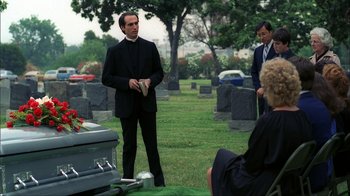 Movie still from “A Nightmare on Elm Street” (1984), directed by Wes Craven – A man standing in front of a grave holding a book; Medium shot, Over the shoulder angle