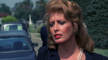 Movie still from “A Nightmare on Elm Street” (1984), directed by Wes Craven – A person wearing a suit and pearls; Close Up shot, Over the shoulder angle
