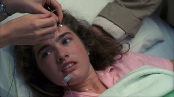 Movie still from “A Nightmare on Elm Street” (1984), directed by Wes Craven – A woman laying in a hospital bed with a thermometer in her mouth; Close Up shot, Overhead angle