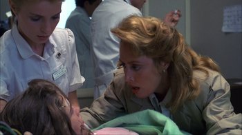 Movie still from “A Nightmare on Elm Street” (1984), directed by Wes Craven – A woman in a brown jacket is talking to a child in a hospital bed; Close Up shot, Over the shoulder angle