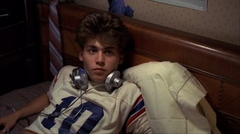 Movie still from “A Nightmare on Elm Street” (1984), directed by Wes Craven – A young man wearing headphones laying in bed; Medium shot, High angle