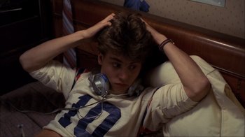 Movie still from “A Nightmare on Elm Street” (1984), directed by Wes Craven – A man laying in a bed wearing headphones; Medium shot, High angle