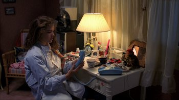 Movie still from “A Nightmare on Elm Street” (1984), directed by Wes Craven – A woman sitting at a table with a phone; Medium shot, High angle