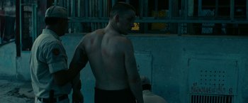 A man with a tattoo on his arm is standing in a room