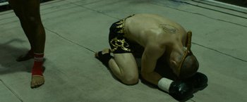 A man with a tattoo is sitting on the ground