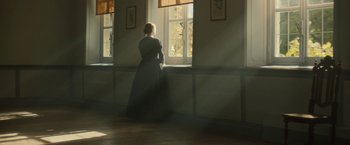 A woman standing in front of a window looking outside