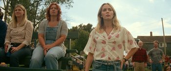 Movie still from “A Quiet Place Part II” (2020), directed by John Krasinski – Two women sitting on a park bench in front of trees; Medium shot, Low angle