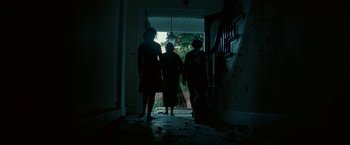 Movie still from “A Quiet Place Part II” (2020), directed by John Krasinski – Three people are standing in a dark hallway; Wide shot, Low angle