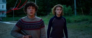 Movie still from “A Quiet Place Part II” (2020), directed by John Krasinski – A boy and a girl standing next to each other in front of trees; Medium shot, Low angle