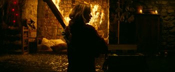 Movie still from “A Quiet Place Part II” (2020), directed by John Krasinski – A woman standing in front of a fire place; Medium shot, Over the shoulder angle