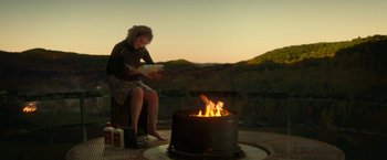Movie still from “A Quiet Place Part II” (2020), directed by John Krasinski – A woman sitting in front of an open fire; Wide shot, High angle