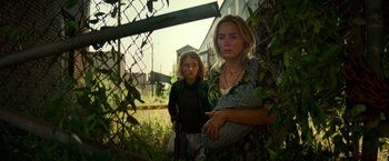 Movie still from “A Quiet Place Part II” (2020), directed by John Krasinski – Two women standing next to each other near a fence; Medium shot, Low angle