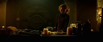 Movie still from “A Quiet Place Part II” (2020), directed by John Krasinski – A woman standing in front of candles in a dark room; Medium shot, High angle