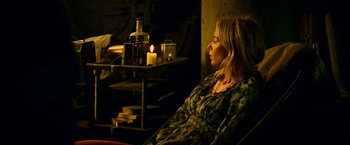 Movie still from “A Quiet Place Part II” (2020), directed by John Krasinski – A woman sitting in front of a candle lit fireplace; Medium shot, High angle
