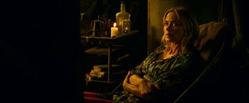 Movie still from “A Quiet Place Part II” (2020), directed by John Krasinski – A woman sitting on a chair in front of a table with candles; Medium shot, Over the shoulder angle