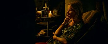 Movie still from “A Quiet Place Part II” (2020), directed by John Krasinski – A woman sitting in front of a candle lit fireplace; Medium shot, High angle