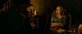 Movie still from “A Quiet Place Part II” (2020), directed by John Krasinski – A woman sitting in a chair in front of a lit candle; Medium shot, Over the shoulder angle