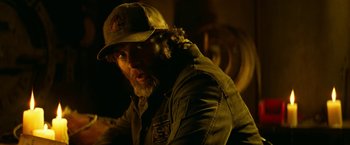 Movie still from “A Quiet Place Part II” (2020), directed by John Krasinski – A man with a beard wearing a hat and jacket; Close Up shot, Over the shoulder angle