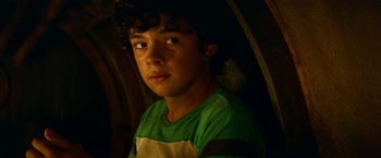 Movie still from “A Quiet Place Part II” (2020), directed by John Krasinski – A young man with curly hair wearing a green t - shirt; Close Up shot, High angle