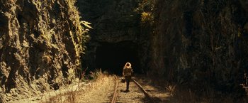 Movie still from “A Quiet Place Part II” (2020), directed by John Krasinski – A person walking on a train track near a tunnel; Extreme Wide shot, High angle