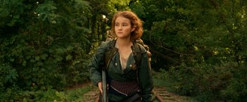 Movie still from “A Quiet Place Part II” (2020), directed by John Krasinski – A young girl with a backpack is walking down the train tracks; Medium shot, Low angle