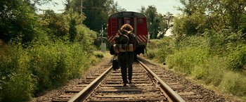 Movie still from “A Quiet Place Part II” (2020), directed by John Krasinski – A person walking down the train tracks with a backpack; Wide shot, Low angle