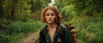 Movie still from “A Quiet Place Part II” (2020), directed by John Krasinski – A young woman with a backpack on a train track; Close Up shot, Over the shoulder angle