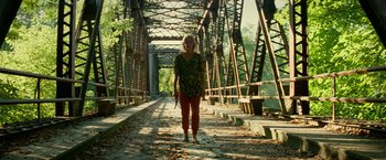 Movie still from “A Quiet Place Part II” (2020), directed by John Krasinski – A woman is standing on a bridge holding a knife; Wide shot, Low angle