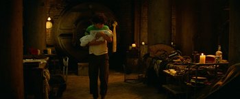 Movie still from “A Quiet Place Part II” (2020), directed by John Krasinski – A man holding a baby in his arms in a dark room; Wide shot, High angle