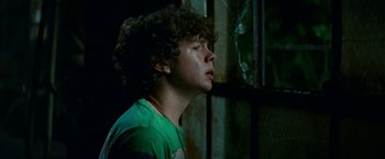 Movie still from “A Quiet Place Part II” (2020), directed by John Krasinski – A young man with curly hair looking out of a window; Close Up shot, High angle