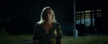 Movie still from “A Quiet Place Part II” (2020), directed by John Krasinski – A woman standing in the dark in front of a building; Medium shot, Over the shoulder angle